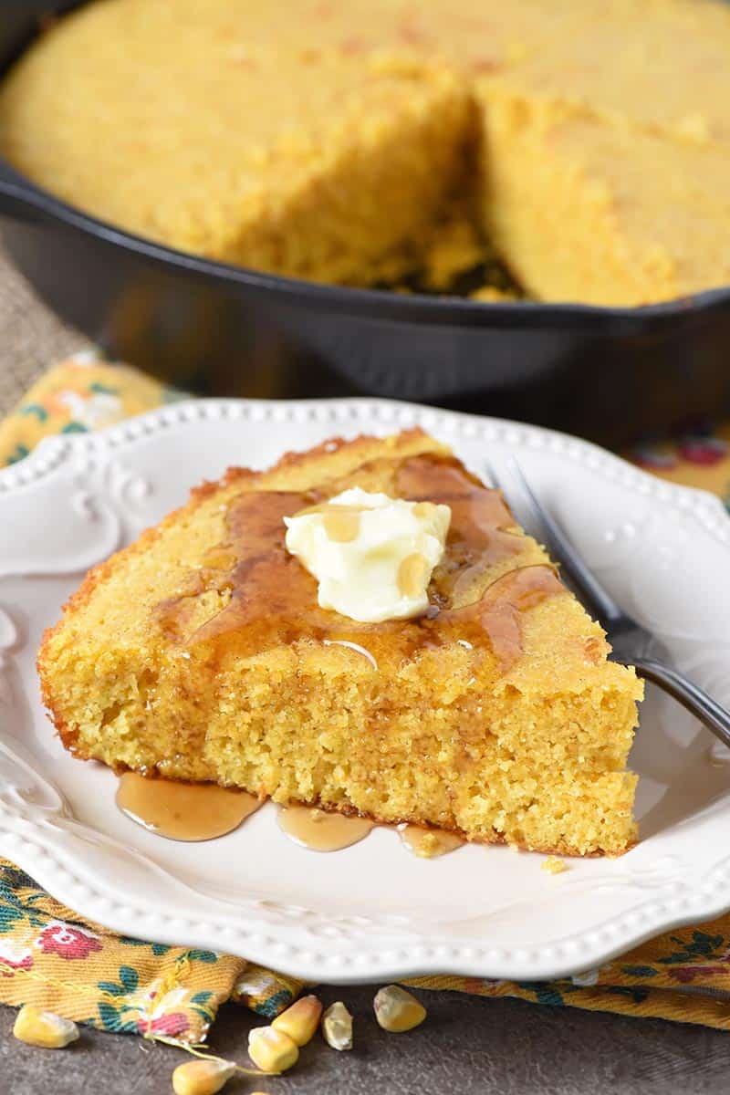 homemade buttermilk cornbread with butter and maple syrup on white plate