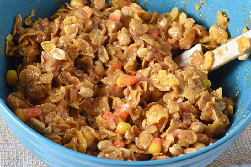 mixing together no bake peanut butter bars in large blue mixing bowl