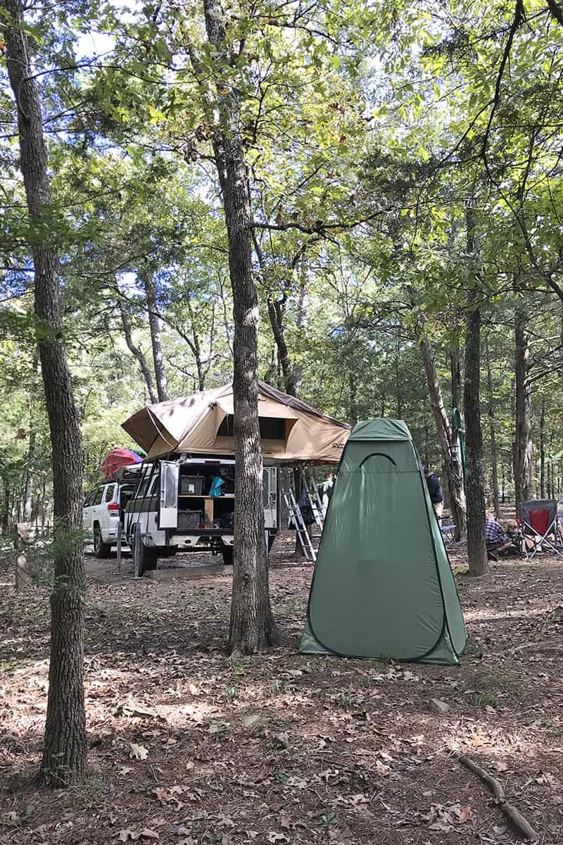 back of campsite at Petit Jean State Park with shower tent and rooftop tent with camping trailer