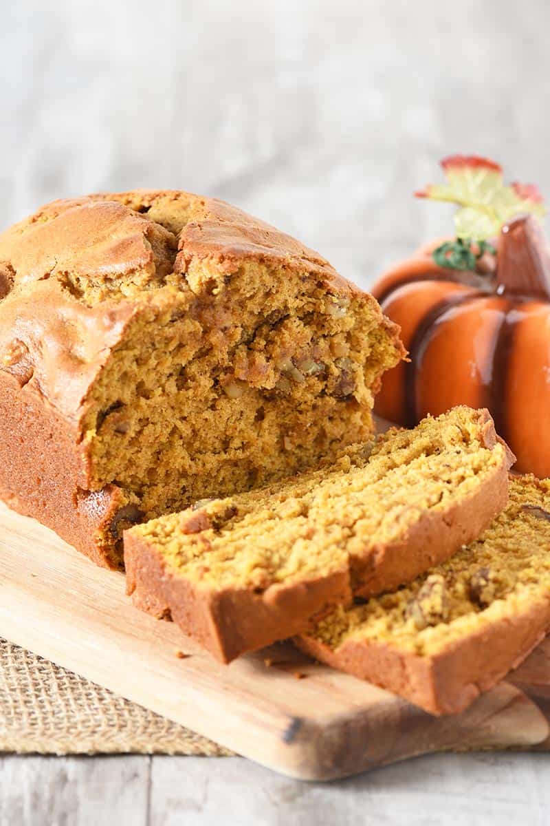 sliced pumpkin bread on cutting board with decorative pumpkin