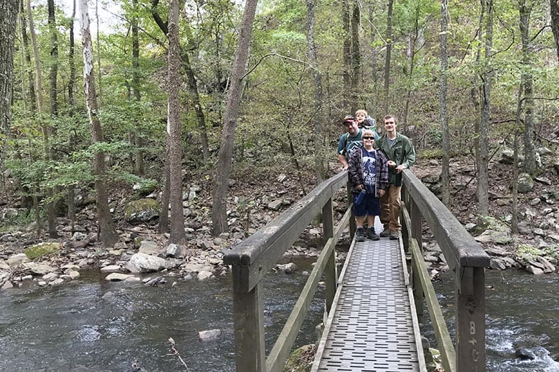 family on footbridge crossing Cedar Creek in Petit Jean State Park, Arkansas