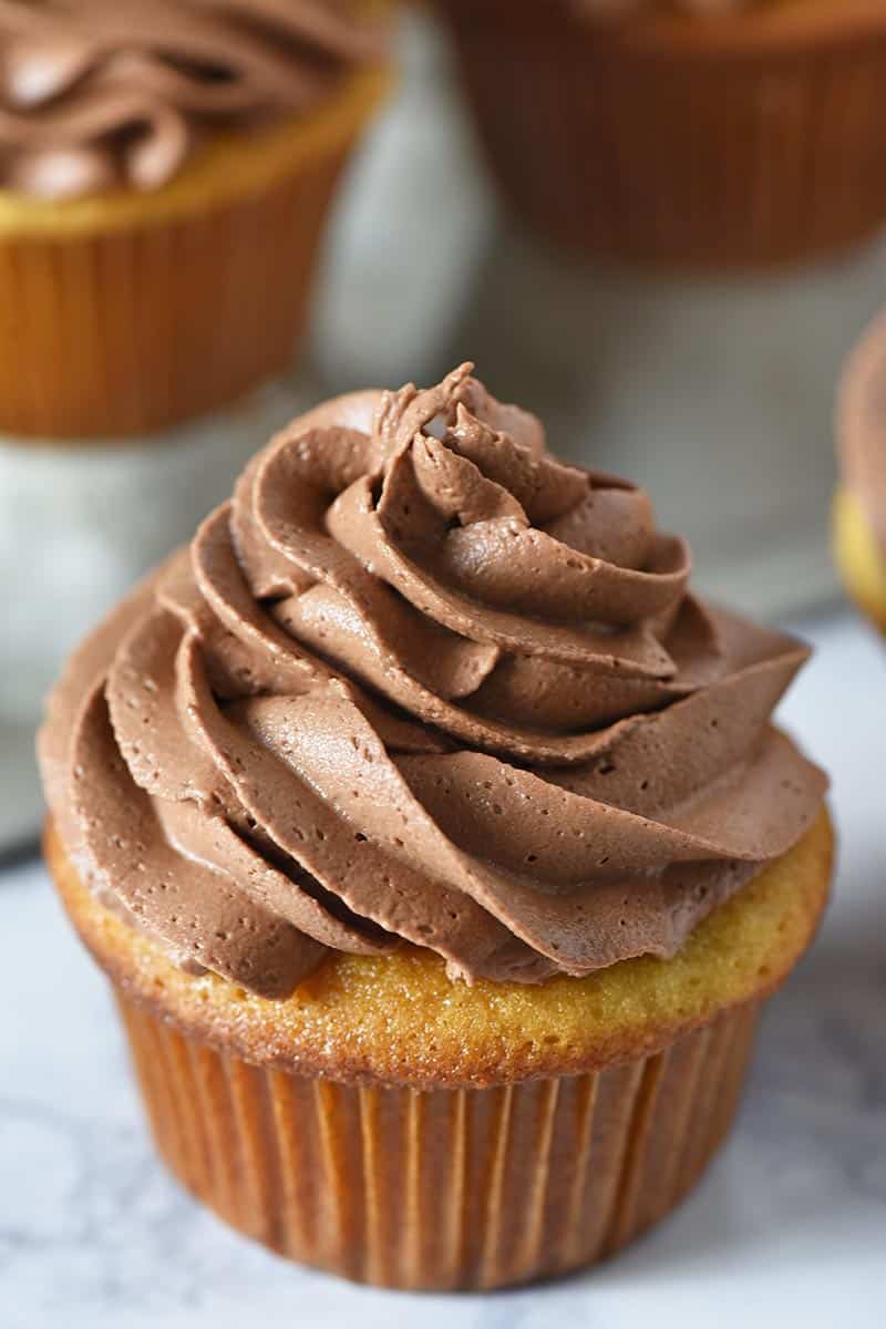 swirled chocolate buttercream icing on top of a yellow cupcake