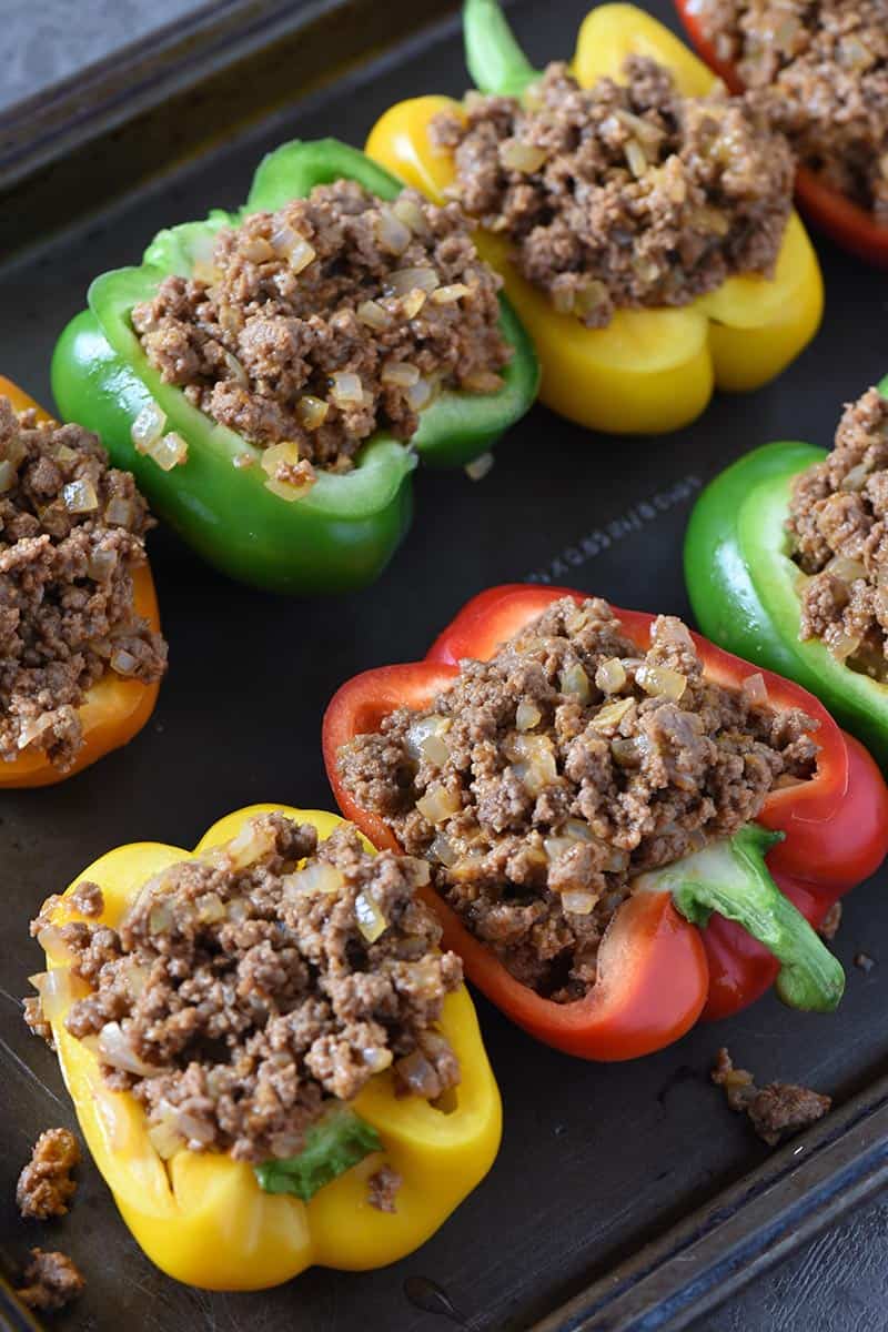 spooning sloppy joe meat into stuffed peppers on baking sheet