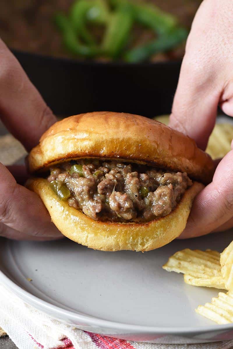 holding a Philly cheesesteak sloppy joe in hands
