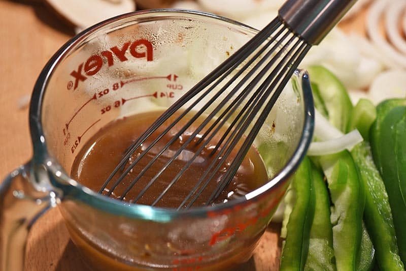 beef broth in Pyrex measuring cup for Philly cheesesteak sloppy joes