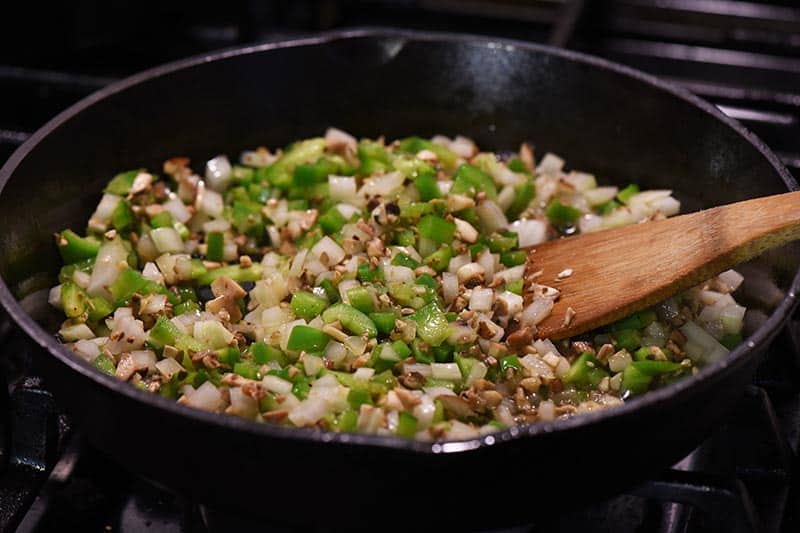 onion, bell pepper, garlic, and mushrooms for Philly cheesesteak sloppy joes cooking in cast iron skillet