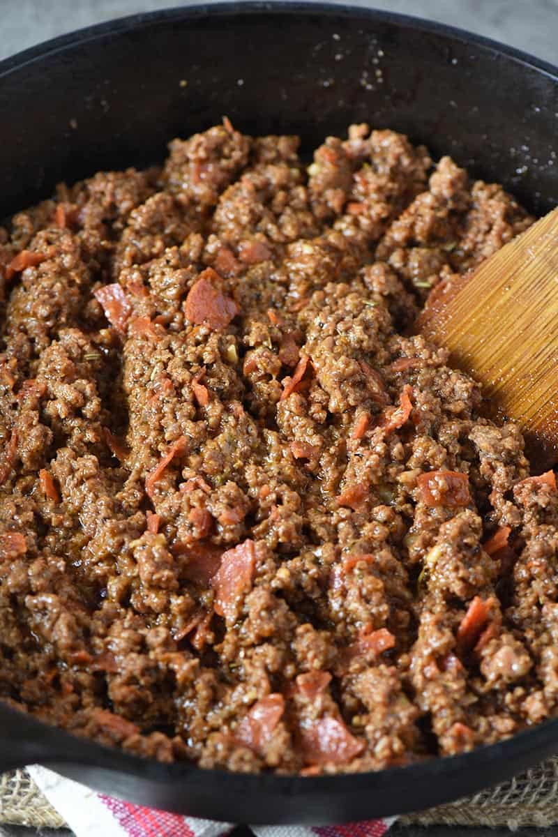 ground beef mixture for pizza joes, with wooden spatula in iron skillet