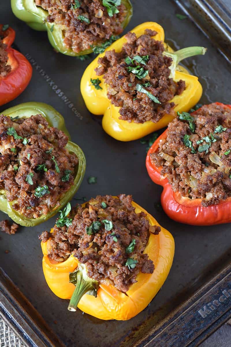 sloppy joe stuffed peppers on baking sheet, garnished with fresh basil