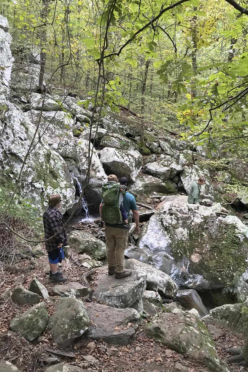hiking around a small waterfall on Cedar Falls Trail in Petit Jean State Park