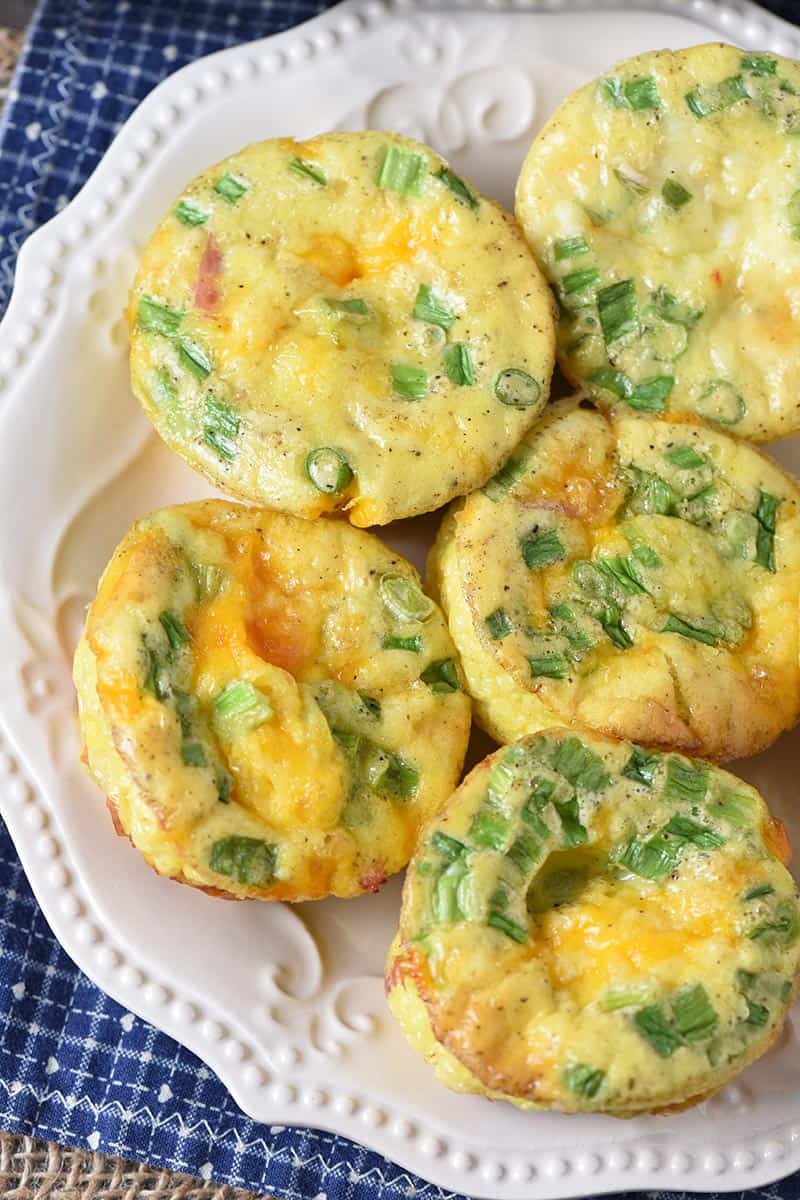 ham and cheese egg cups on white plate with blue cloth