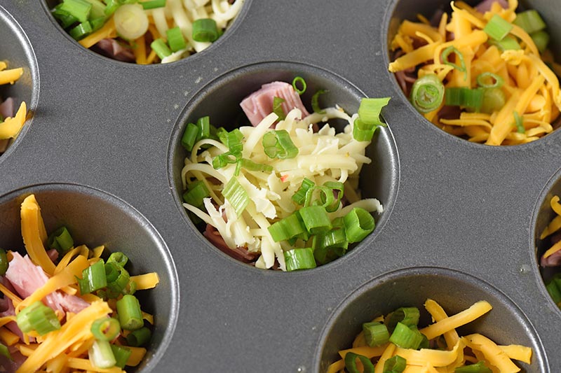 adding green onions with ham and cheese for egg muffin recipe
