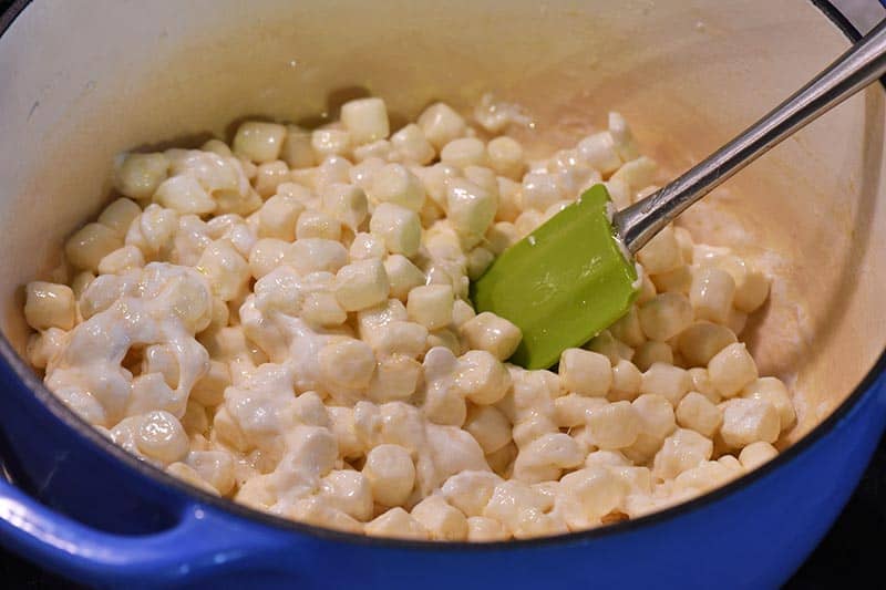 making Rice Krispies treats by melting mini marshmallows in butter and vanilla mixture in blue Dutch oven
