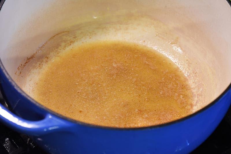 melting butter and mixing with vanilla extract to make Rice Krispie treats recipe in blue Dutch oven