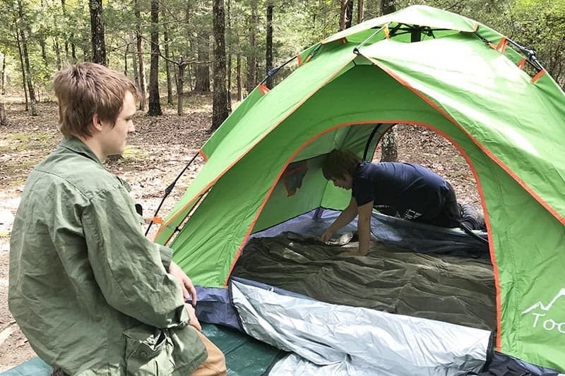boys airing up the air mattress in a green pop up tent at Petit Jean State Park