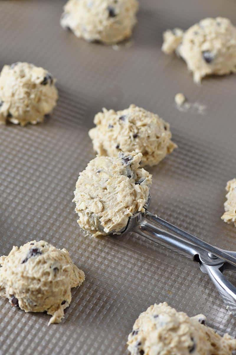 cookie scoop with best oatmeal chocolate chip cookie dough on cookie sheet