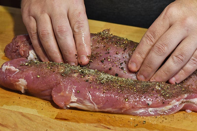 rubbing salt and pepper into pork tenderloin before roasting