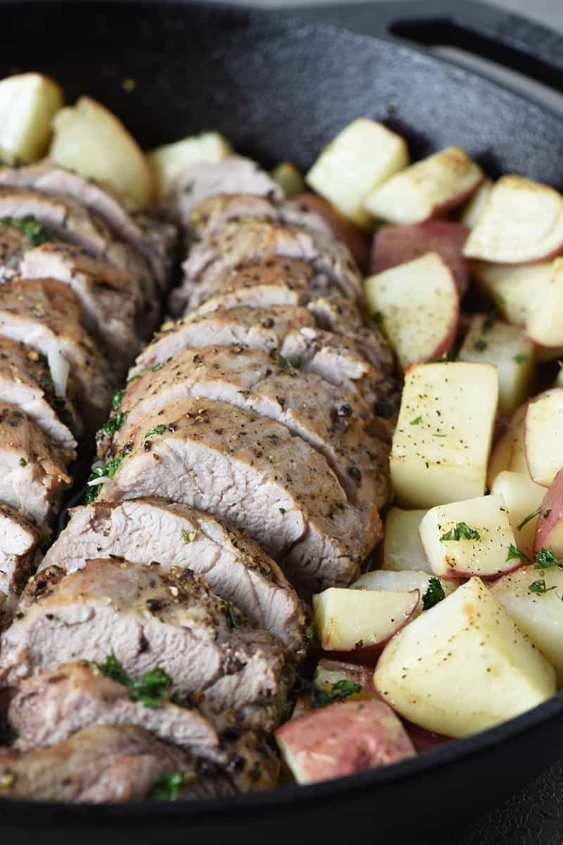 sliced pork tenderloin with tender roasted potatoes in cast iron skillet