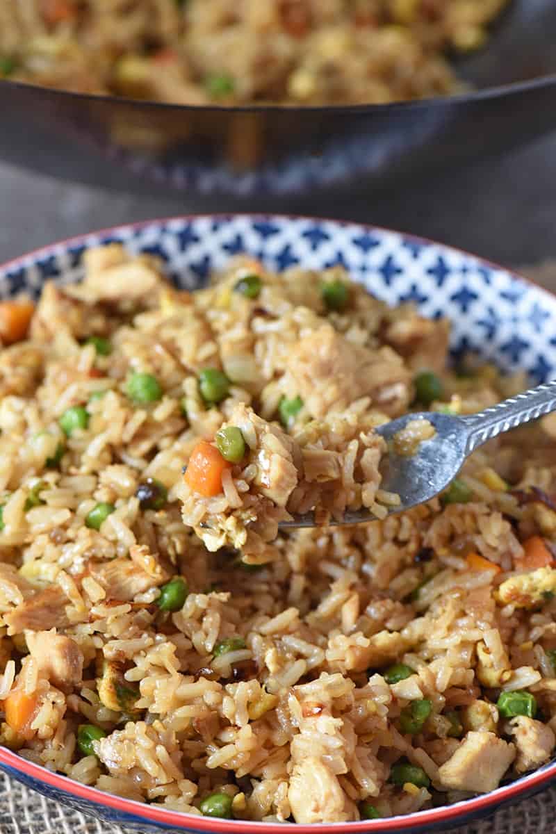 fork with bite of easy chicken fried rice wok style over big bowl of rice