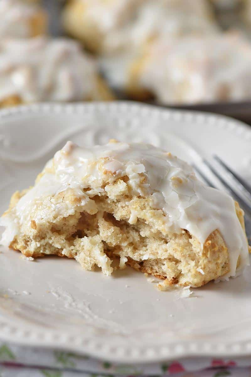 cinnamon biscuit split in half, lightly frosted, on white plate