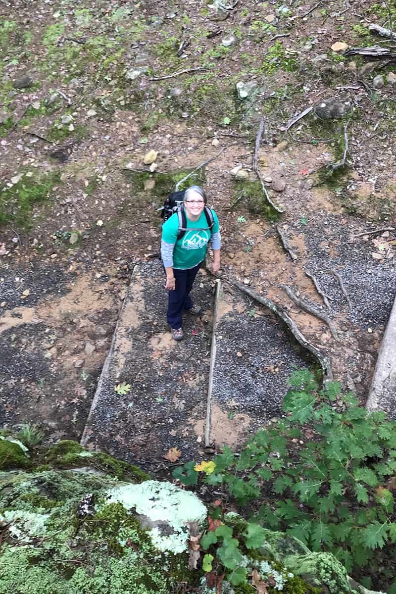 woman with backpack hiking Bear Cave Trail in Petit Jean State Park, Arkansas
