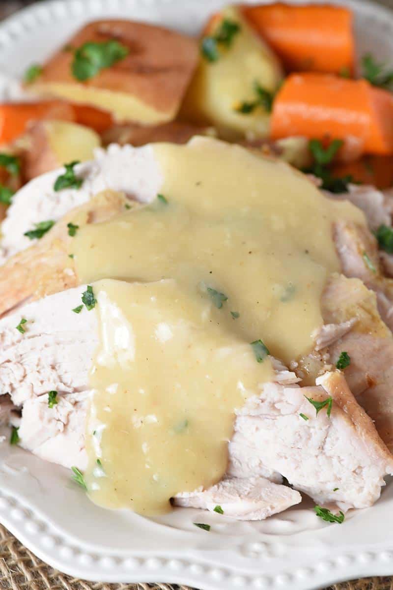 pork gravy over sliced pork roast on white plate with vegetables