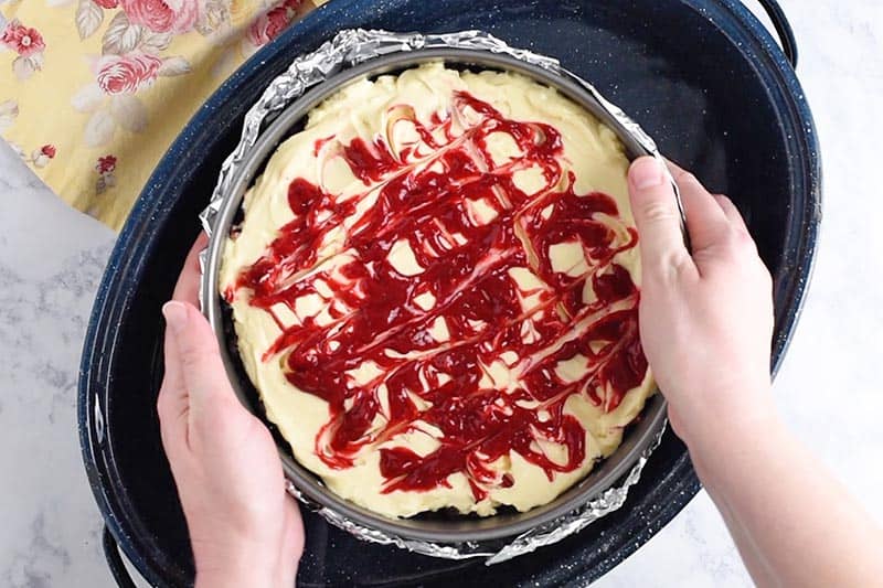 placing foil wrapped raspberry cheesecake into turkey roasting pan with about an inch of water