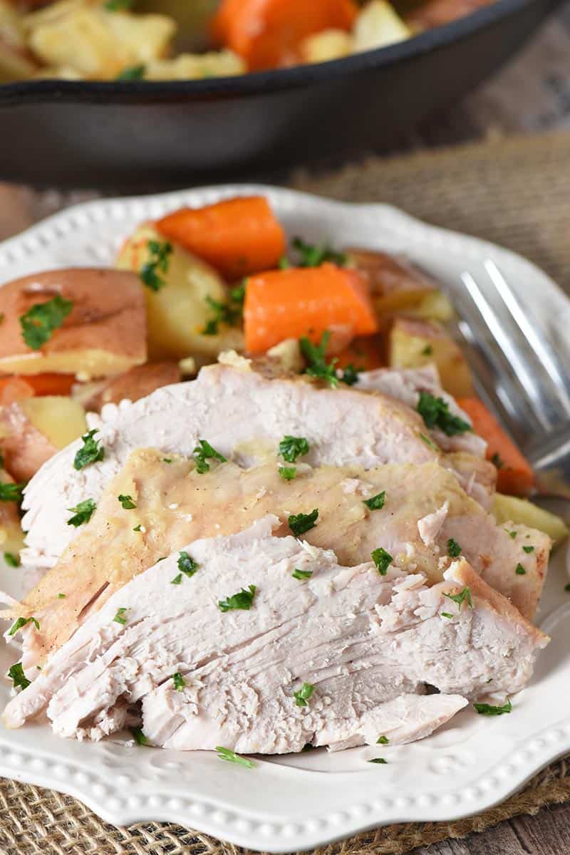 sliced pork roast with vegetables on white plate