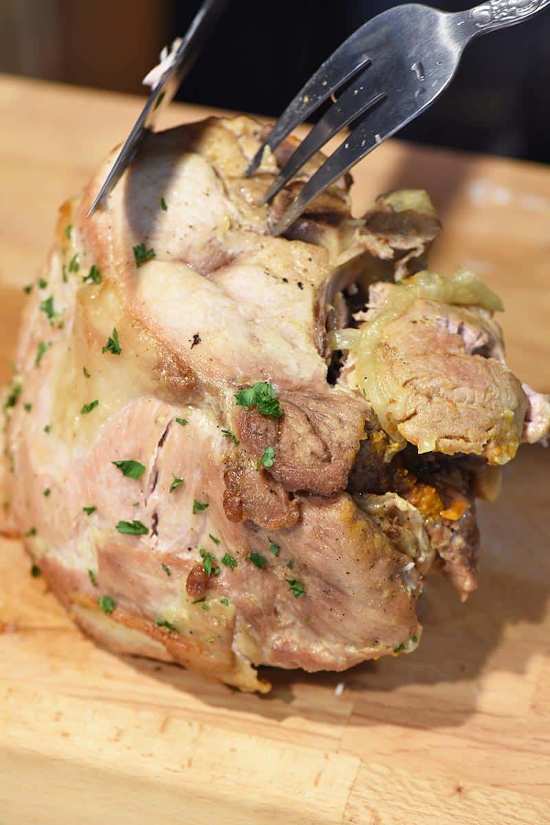 slicing pork roast on wooden cutting board