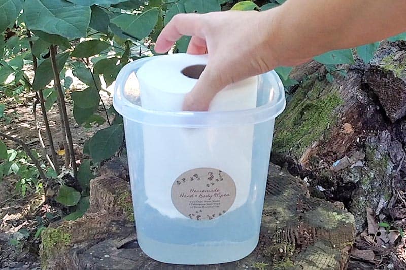 adding half roll of paper towels while making homemade camping bath wipes in plastic canister