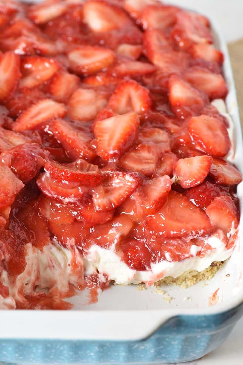 scooped or sliced strawberry delight yum yum dessert in blue and white baking dish