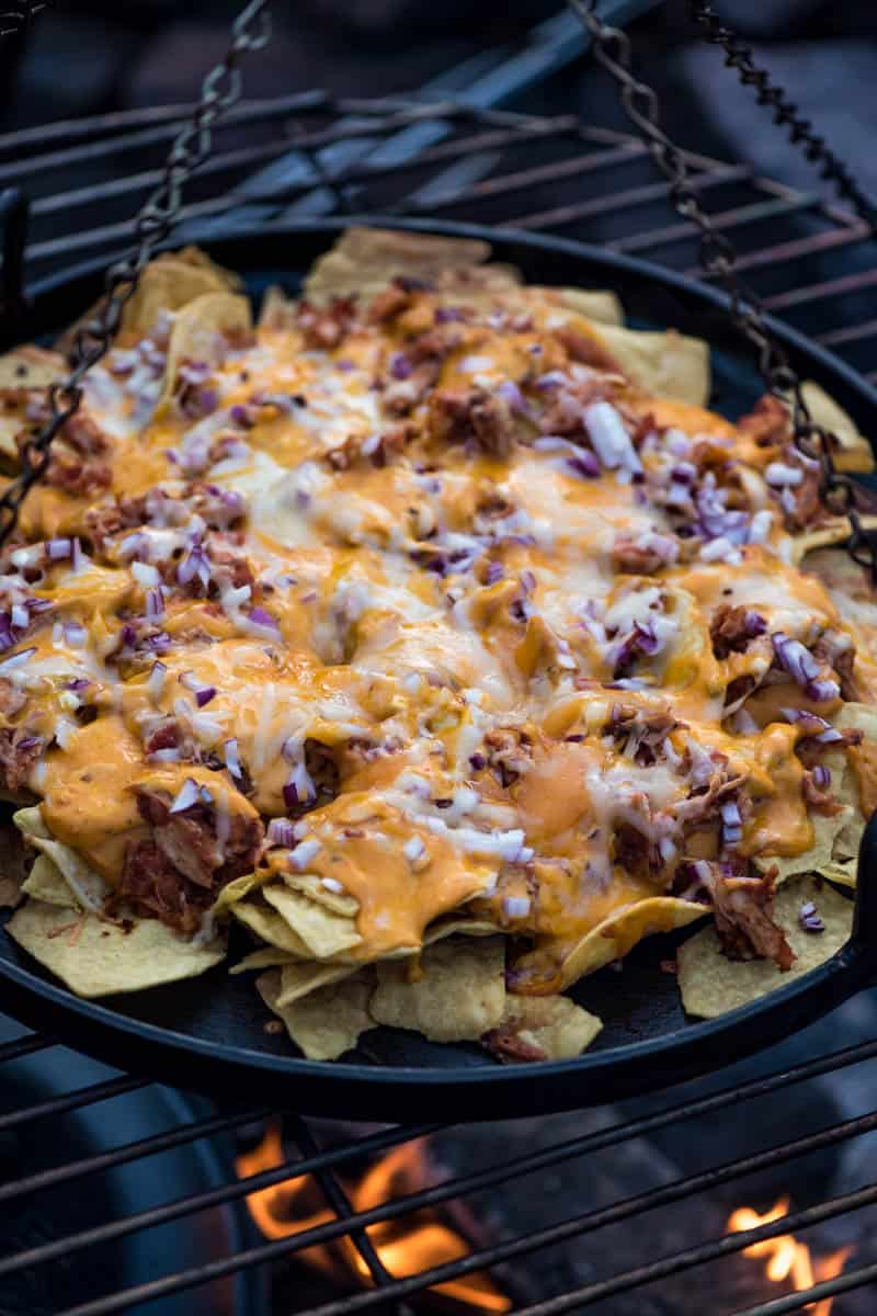 melted cheesy nachos in cast iron pan on campfire grill
