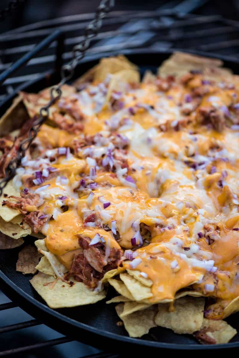 cooking chicken nachos over campfire using campfire cooking equipment like a cast iron pizza pan or griddle