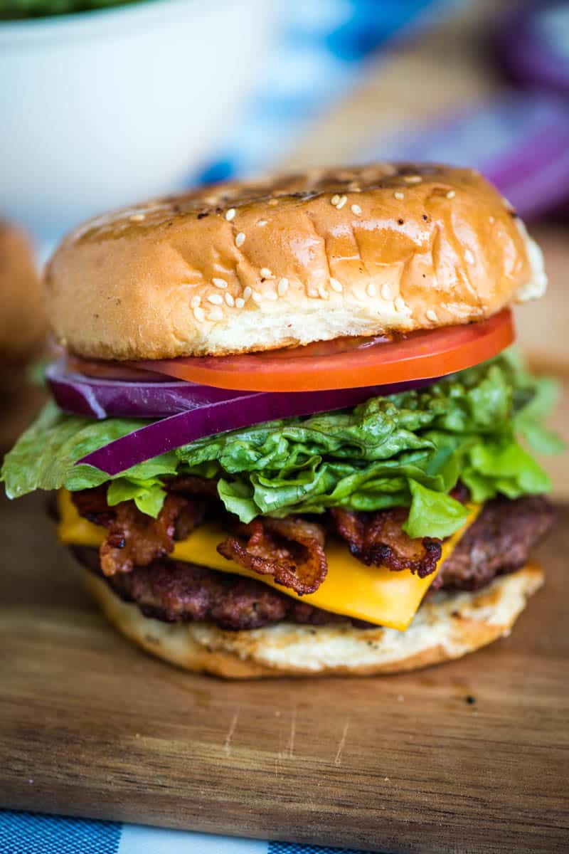 loaded bacon cheeseburger with toasted buns on wood cutting board