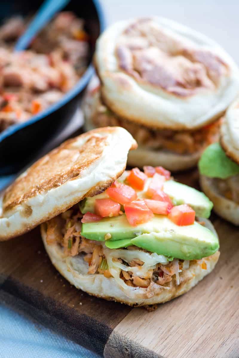 English muffin tuna melt sandwich with avocado and tomatoes on wooden cutting board