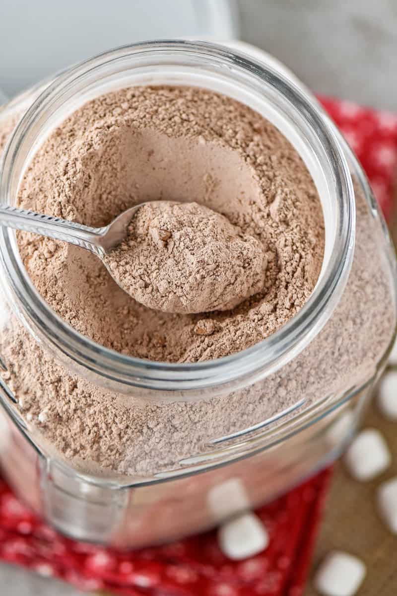 homemade hot chocolate mix in a large glass jar on a red tablecloth
