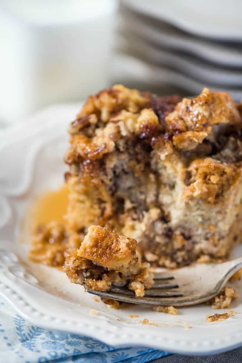 bite of CrockPot cinnamon French toast on fork on white plate with maple syrup