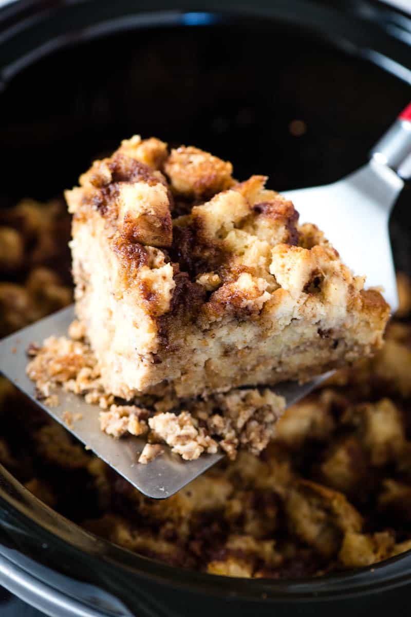 slicing and scooping slow cooker French toast out of Crock Pot with wide flipper spatula