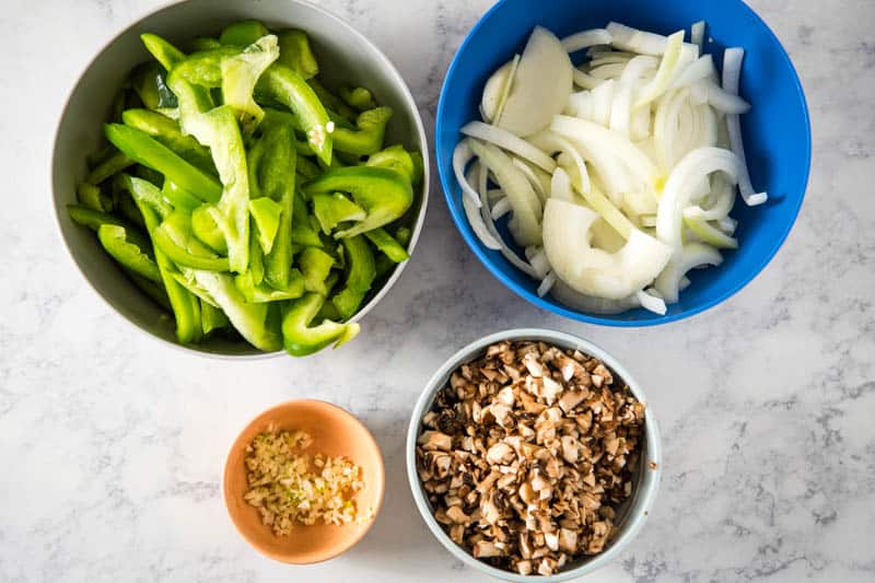 bowls of green bell peppers, yellow onion, garlic, and minced mushrooms for CrockPot Philly Cheesesteak