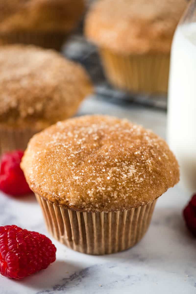 Bisquick cinnamon muffins sitting on white marble countertop with fresh red raspberries and glass of milk