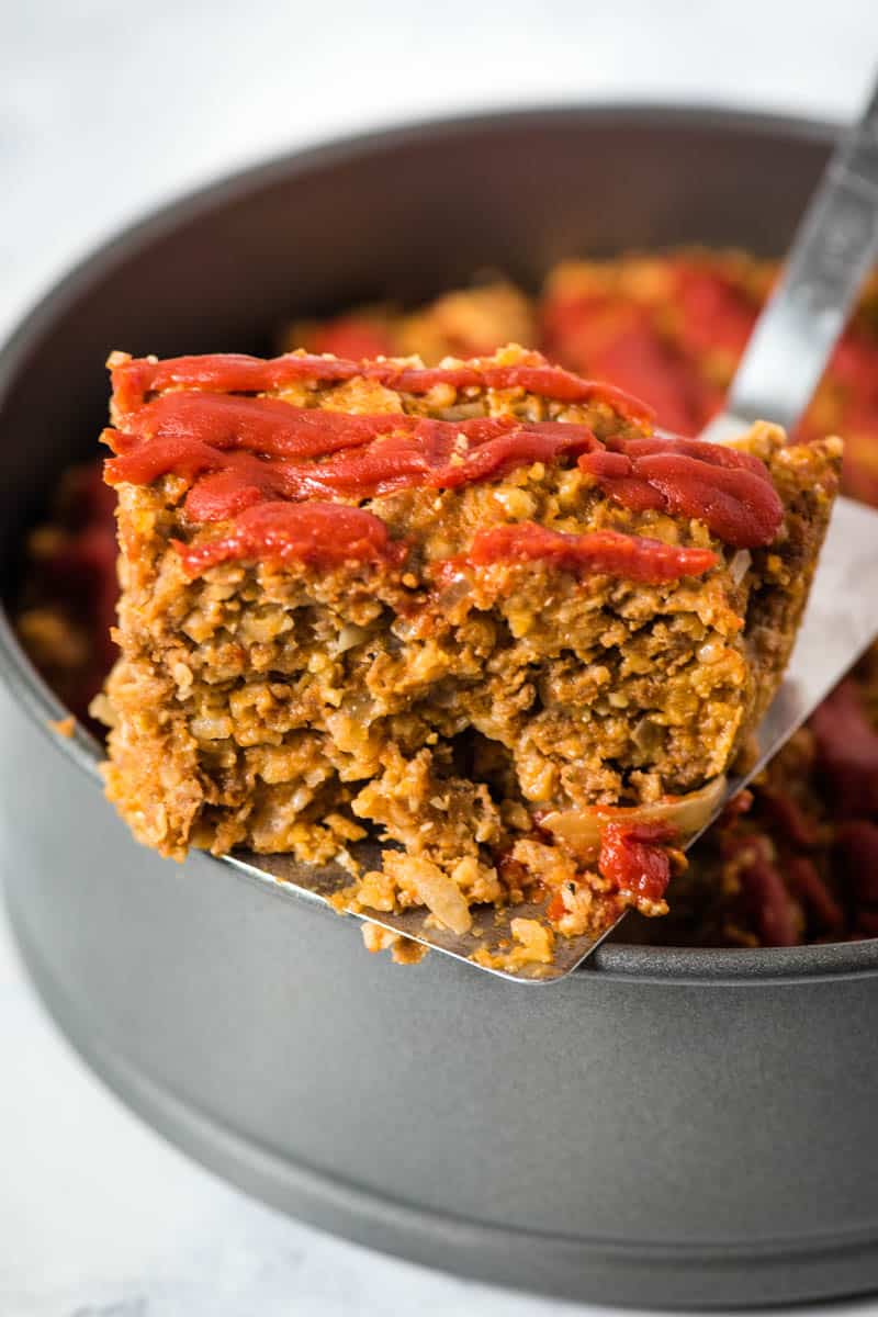 slicing and serving Instant Pot meatloaf with oatmeal from springform pan with metal spatula flipper