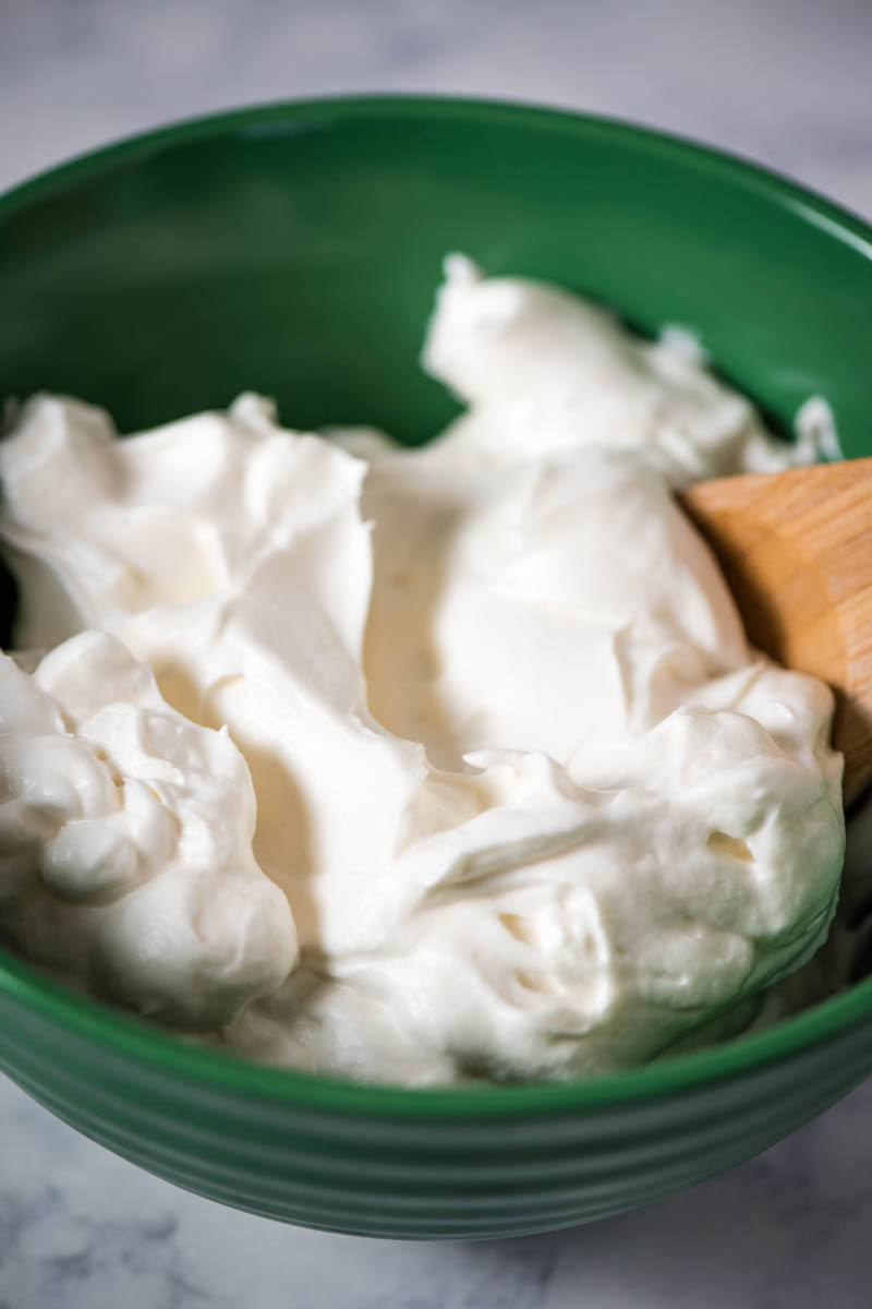 Dream Whip whipped dessert topping in green mixing bowl with wooden spoon