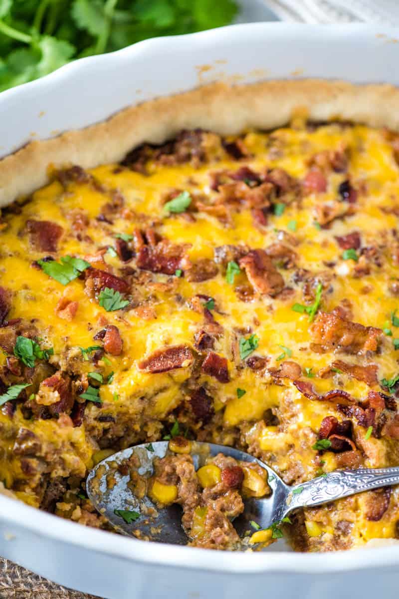 baked Mexicali meat pie in white casserole dish with large spoon