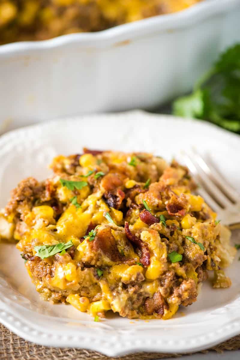 serving of cheesy Mexican casserole with bacon on white plate with fork