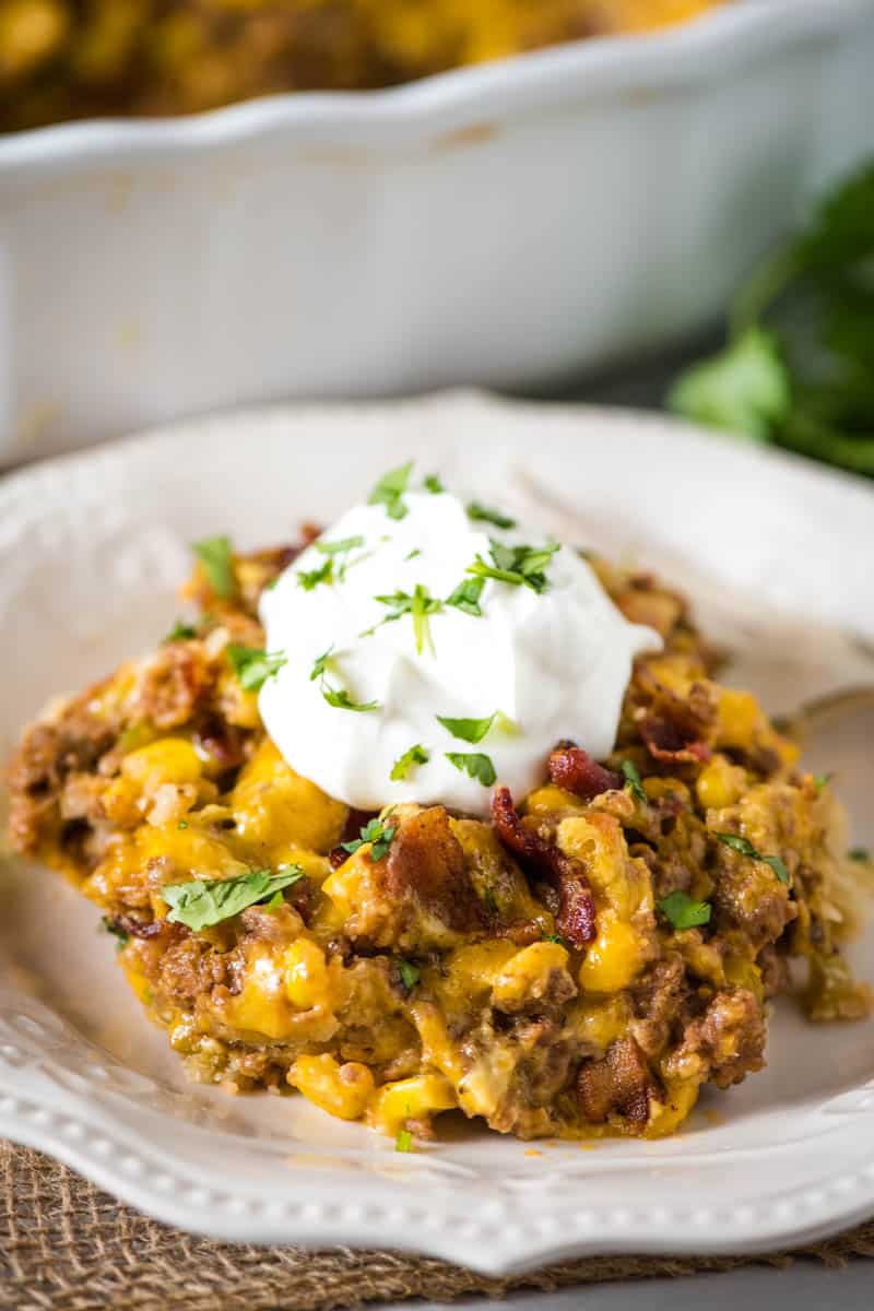serving of Mexican pie, topped with sour cream and cilantro, on white plate with fork