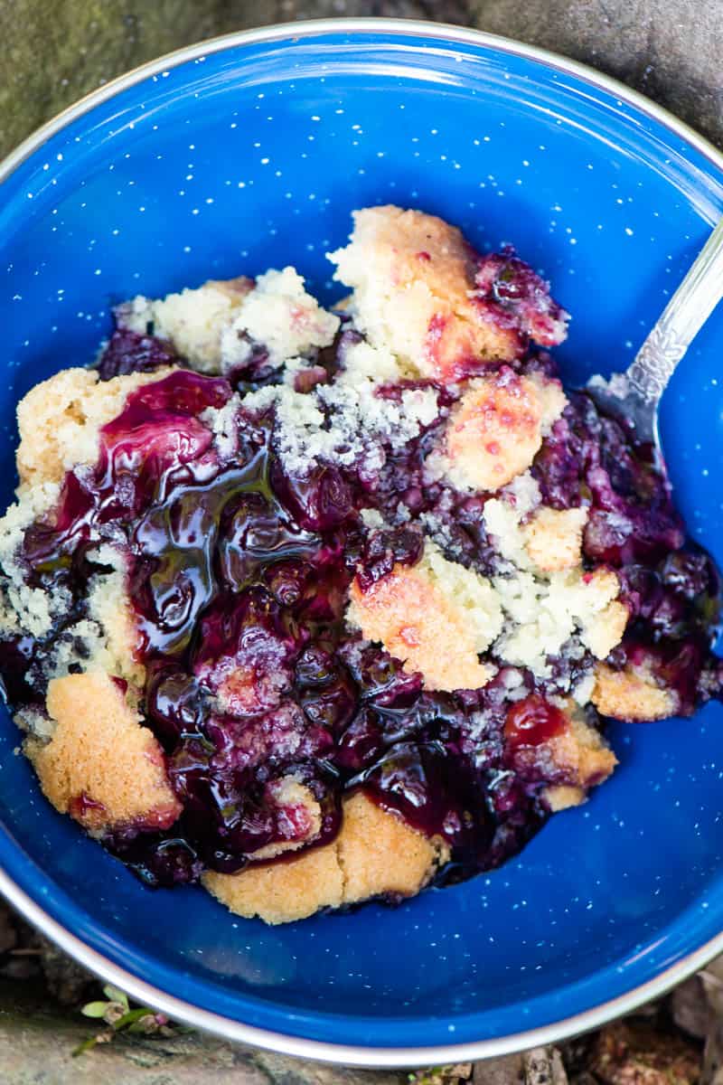 camping blueberry cobbler in blue enamel bowl with spoon
