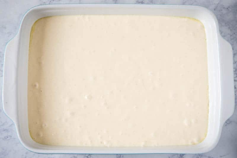 white cake batter in 9x13 baking dish on white marble countertop