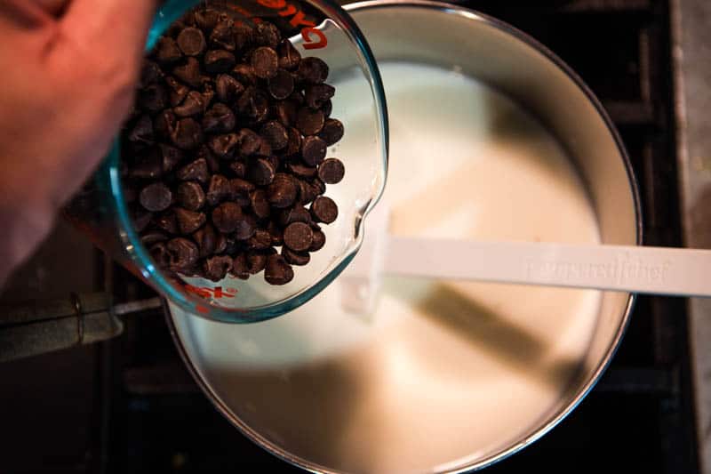 adding chocolate chips to milk in saucepan to make hot chocolate from chocolate chips