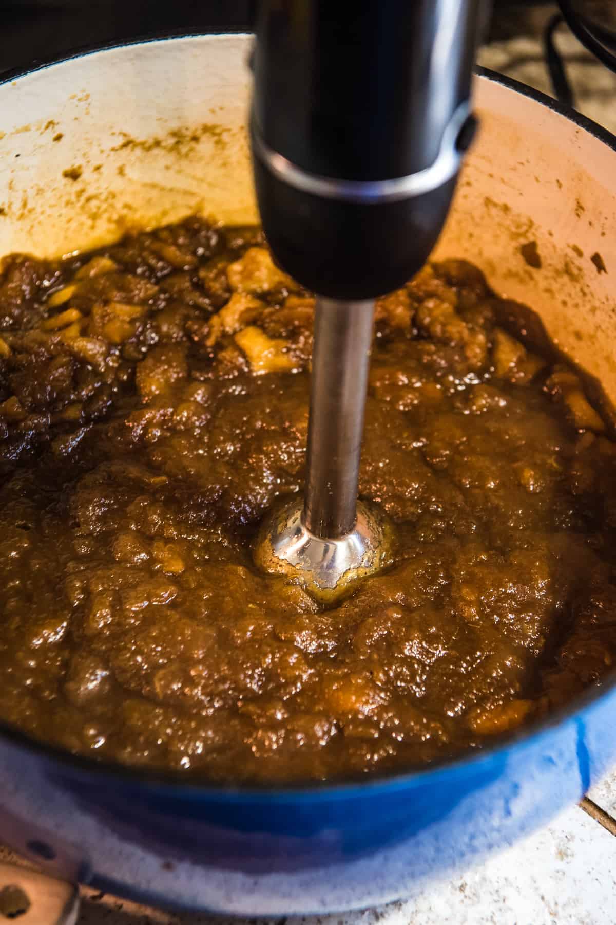 blending stovetop apple butter in blue Dutch oven with immersion blender