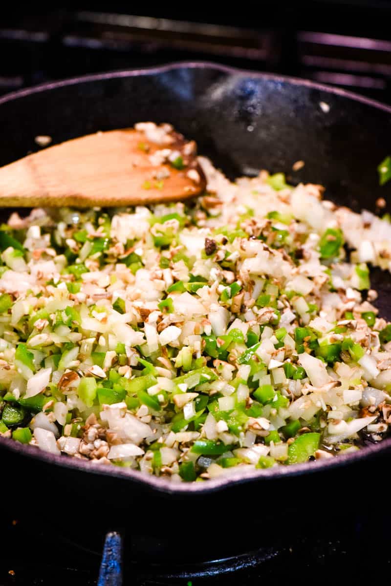 sautéing peppers and onions and mushrooms for cheesesteaks in cast iron skillet with wooden spatula