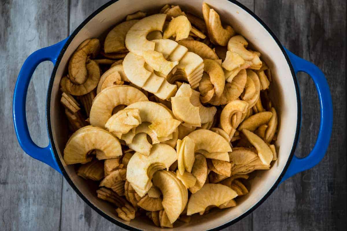 peeled and sliced apples for apple butter in blue Dutch oven